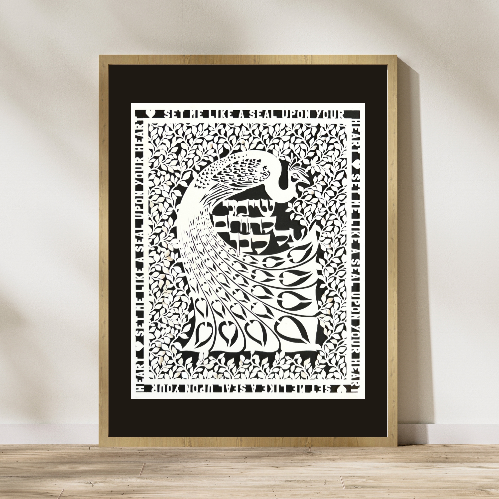 Simply framed papercut art against a black mat. Set me like a seal upon your heart runs along the outer edge of the papercut. At the center of the Art Nouveau-inspired papercut is a peacock, tiny leaves surround it, and the Hebrew text for the quote sits between the peacock's curved tail and body. The papercut is white against a black background